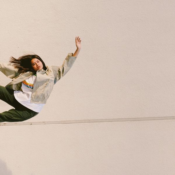 Person in a balanced yoga stance against a dark, minimalist background.