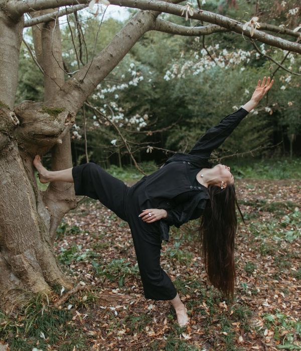 Woman performing a gentle yoga pose in a calm, dark environment.
